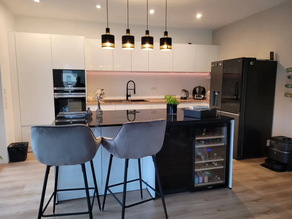 Referenzbild einer hellen, moderne Küchenzeile mit Kücheninsel. Gesamteindruck mit Blick auf die Insel und den integrierten Weinkühlschrank