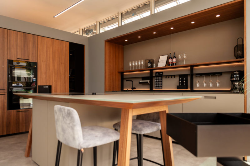 Next125 Küche mit Kochtisch und Barhockern holzfarbend gehalten