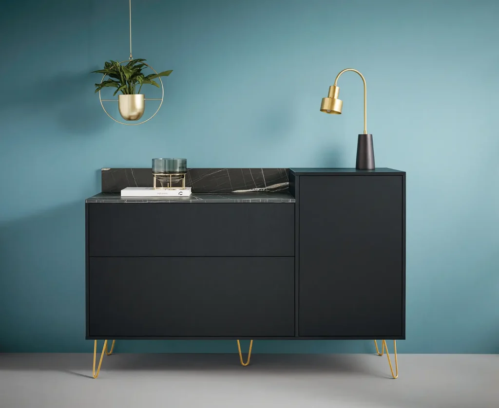 Ein modernes schwarzes Sideboard von Schüller Möbel mit goldenen Beinen steht vor einer blauen Wand. Darauf stehen eine goldene Lampe, ein Buch und eine Zierpflanze. Über dem Sideboard hängt ein hängender Pflanzkübel mit einer grünen Pflanze, der diese stilvolle Anordnung zeitgenössischer Wohnmöbel abrundet.